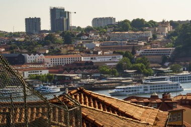 Porto şehrinin yüksek manzarası, kırmızı kiremit çatıları, nehir kenarındaki binalar ve Douro Nehri 'ndeki yolcu gemileri, gün ışığı altında..