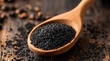 black sesame seeds and spoon on wooden background