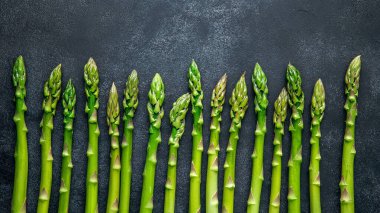 Koyu arkaplanda taze organik yeşil kuşkonmaz.