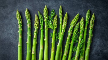 Siyah arka planda su damlaları olan taze kuşkonmaz..