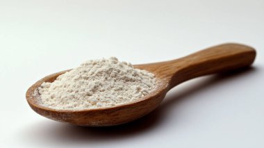 Tahta arka planda beyaz un kaşığı.