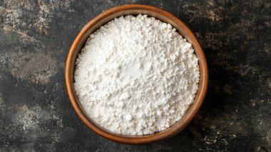 Siyah arka planda beyaz bir kase un.