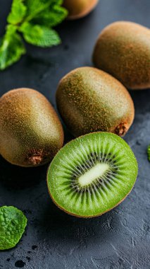 Koyu arkaplanda yaprakları olan taze kivi meyvesi..