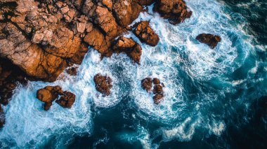 Dalgalar ve köpüklerle deniz kıyısının havadan görünüşü.