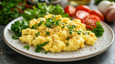 Çırpılmış yumurta ve siyah tabakta otlar. Kahvaltı