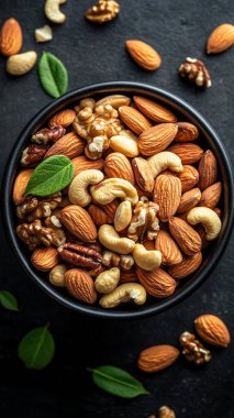 Koyu arkaplanda badem ve fındık kâsesi.