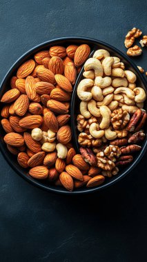 Sağlıklı yemek. Koyu taş masa manzaralı fındıklı kase, kurutulmuş meyve ve badem.