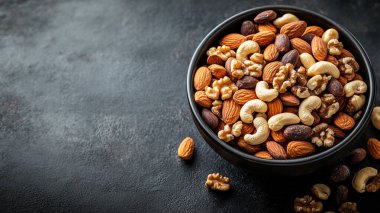 Sağlıklı yemek. Kurutulmuş meyveli bir kase kuru badem fıstığı. Siyah bir arkaplanda.