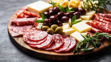 Siyah ahşap arka planda farklı salam ve peynir çeşitleri.