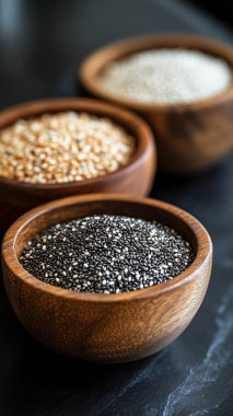 Tahta bir kasede, siyah arka planda çeşitli buğday taneleri, üst manzara. organik gıda kavramı.