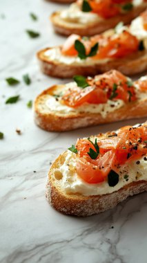 Krem peynirli, somonlu, domatesli, gri masadaki otlu, düz yataklı lezzetli sandviçler.