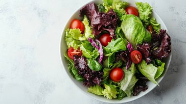 domatesli sağlıklı salata, kırmızı soğan ve fesleğen beyaz bir tabakta gri beton arka planda.