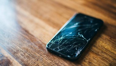 Ahşap masanın arka planında kırık cam telefon..