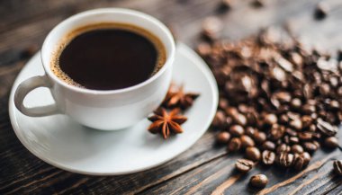 cup of hot coffee with cinnamon sticks on a table.