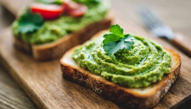 Tahta bir masada taze ot ve baharatlı avokado tostu, sağlıklı yemek, vejetaryen atıştırması, sağlıklı beslenme, diyet, vejetaryen ve sağlıklı yemek.