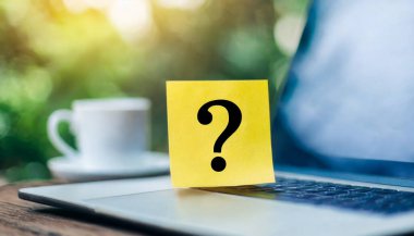 Soru işareti ve soru işareti olan tahta küplerdeki soru işaretleri dizüstü bilgisayarda.