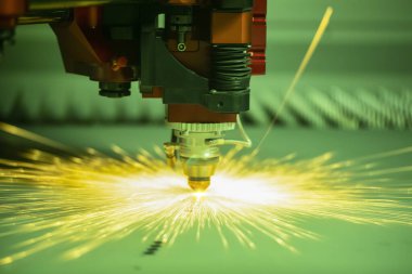 Metal işleme için otomatik programlanmış makine. Endüstriyel lazer makinesi çelik levha parçalarını kesiyor. Sıcaklık. Fabrikadaki üretim makinesinin çalışması sırasında kıvılcımlar.