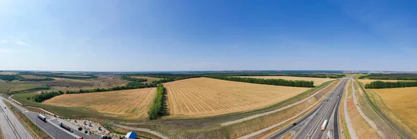 Aerial photography of agricultural fields in Russia. Beautiful views. Highway along the fields. Sunny day.