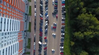 Bir İHA hareket halindeki arabalarla yol üzerinde uçuyor. Orman ve yüksek binalar.