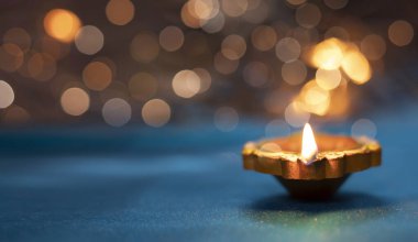 Işık saçan arka planda yansıtıcı bir tabanda Diya lambaları