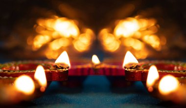 Işık saçan arka planda yansıtıcı bir tabanda Diya lambaları