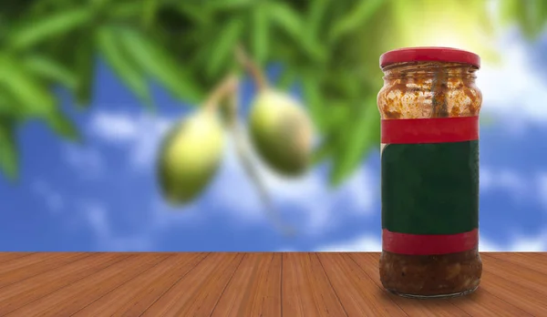 A jar of spicy mango pickle on a wooden table surface against the natural backdrop