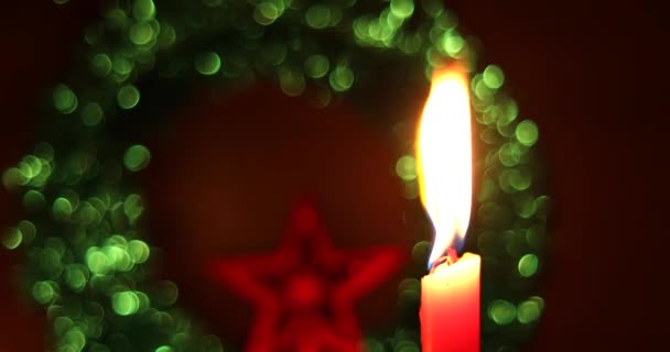 Χριστουγεννιάτικα στολίδια με κερί. Ένα μεμονωμένο κερί ανάβει με ένα σκοτεινό αφηρημένο φόντο bokeh. — Αρχείο Βίντεο