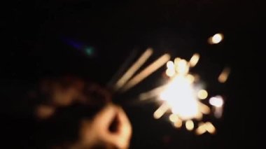 Kaygısız insanlar. Parıldayan Ellerde Parıldayan Yanık Maytap Rengi ile gerçek bir eğlence. Erkek ya da Kadın Sıradan Funky Kutlaması. Hint Titreşimi Bulanık Bokeh