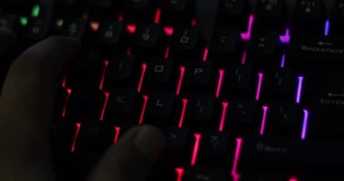 Parlak RGB oyun klavyesinde karanlıkta yazarken eli kapat