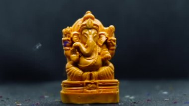 Hindu tanrısı Ganapati 'nin heykelinin üzerine parlak, saçılmış konfeti folyo simleri düştü. Seçici odak