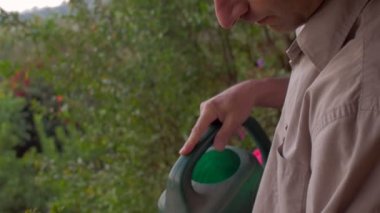 Orta yaşlı adam yeşil bir sulama olabilir ile açık bir bitki sulama.