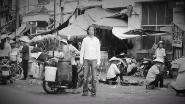 HANOI, VIETNAM - CIRCA JUNE 2015 - Time-lapse of man standing still at a busy market as the world whizzes by him — Stock Video