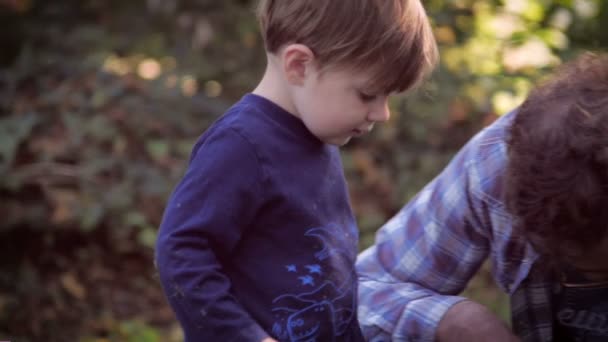 Pai e filho descobrindo algo no chão juntos em slo mo — Vídeo de Stock