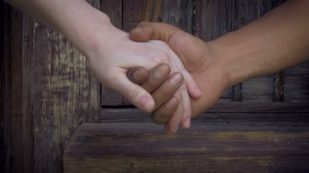 Mãos brancas e pretas abraçam amorosamente na frente de uma bela porta antiga — Vídeo de Stock