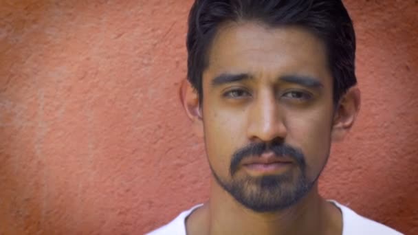 Портрет молодого красивого латиноамериканца у оранжевой стены — стоковое видео