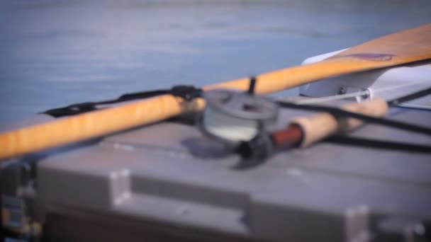 Foco de cremalheira de uma vara de pesca da mosca que descansa em uma canoa durante uma viagem de pesca — Vídeo de Stock