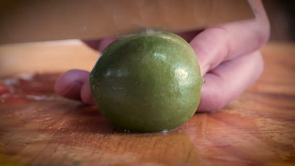 Close up de mãos cortando abrir um limão fresco com uma faca chef em uma tábua de corte — Vídeo de Stock