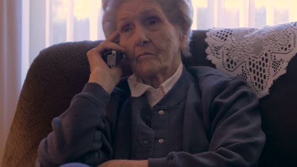 Слепая пожилая женщина в своем доме слушает по телефону выглядит серьезно в 4K куклу — стоковое видео