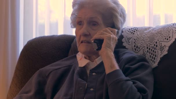 Una anciana de 90 años habla y se ríe en un teléfono en su casa en 4k dolly — Vídeo de stock