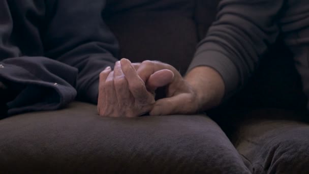 An elderly son holds his mother's hand on a sofa - dolly shot in 4k — Stock Video