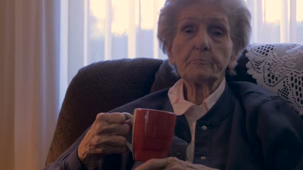 Uma mulher idosa conta uma história enquanto bebe uma xícara de café - boneca baleada em 4k — Vídeo de Stock