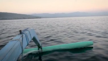 Arka planda dağlar ile su yüzeyine kaymağını tekne