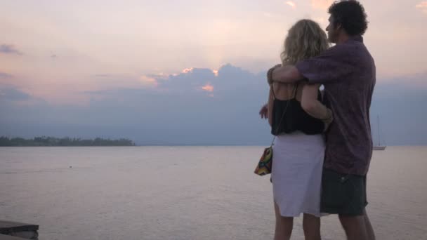 Старша красива пара обіймається з видом на захід сонця над океаном — стокове відео