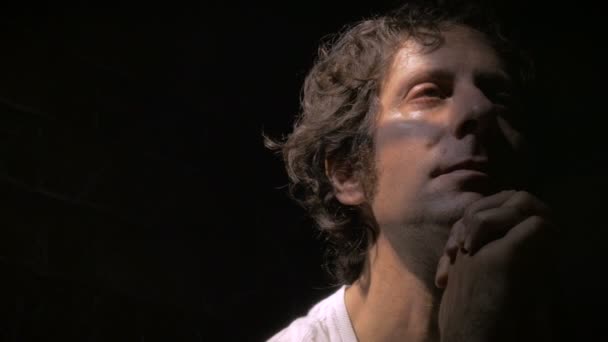 Dolly fotografió a un hombre rezando y mirando hacia arriba con una iluminación dramática — Vídeos de Stock