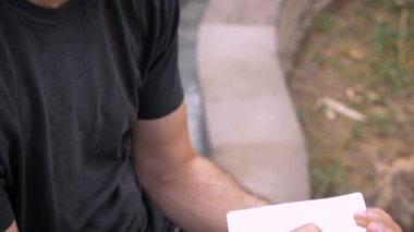 Adam bir yüzme havuzu yanında bir kalem ile küçük bir not defterinde yazıyor