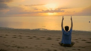 Silah düşürerek ve uzanarak okyanus, lotus yoga poz oturan bir adam