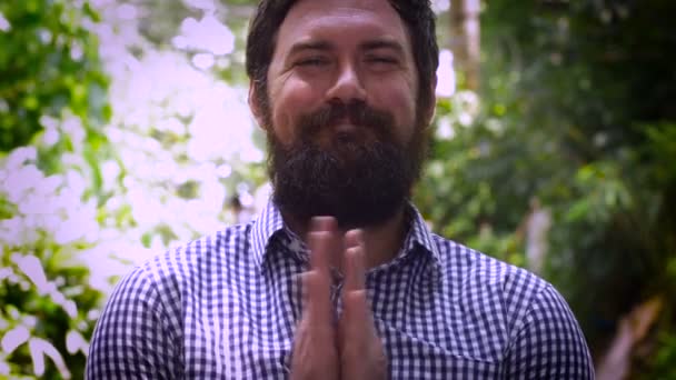 Retrato de um homem barbudo com um sorriso bobo e mãos batendo palmas firmemente juntas — Vídeo de Stock