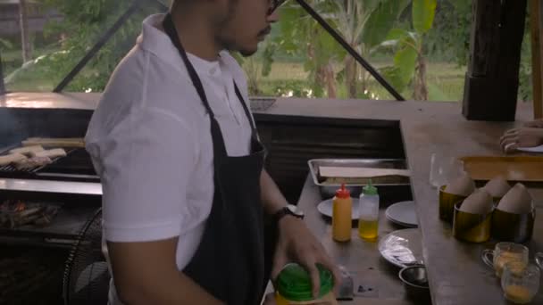 Een werknemer van het restaurant bereidt een oranje saus in een grote plastic pot — Stockvideo