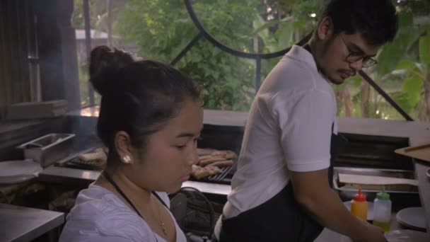 Handheld shot of two restaurant workers preparing food at a counter — Stock Video