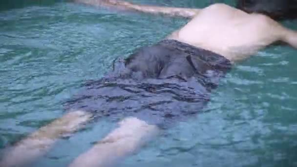 Hombre flotando boca abajo en una piscina — Vídeo de stock